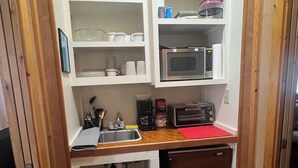 A compact kitchen with a microwave, toaster, sink, and a small refrigerator. - Cozy Cabin on Angelina River near Lake Sam Rayburn-Pool, Boat Parking, Fishing (Jasper)