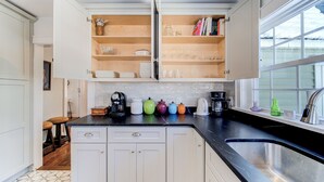 Une cuisine avec des meubles blancs, un plan de travail noir et une fenêtre donnant sur un beau paysage.