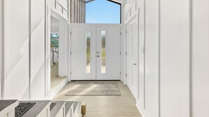 A modern hallway with white walls, a geometric patterned rug, and a skylight above a double door. - Private Pool/Spa! 4 Min Walk to Vilano Beach. Two Living Rooms & Kitchens (St. Augustine)