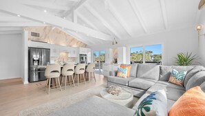 A modern living room with a grey sectional sofa, a coffee table, and a dining area with bar stools. - Private Pool/Spa! 4 Min Walk to Vilano Beach. Two Living Rooms & Kitchens (St. Augustine)