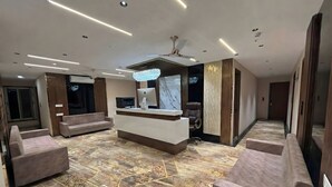 Un vestíbul modern amb taulell de recepció, zona de seients i un penjall decoratiu.