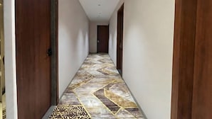 Un passadís amb paviment decoratiu, portes de fusta i un sostre amb llums empotrades.