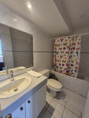 A bathroom with a white sink, mirror, toilet, and shower curtain with a butterfly pattern. - Cavancha peninsula Royal marine building (Iquique)