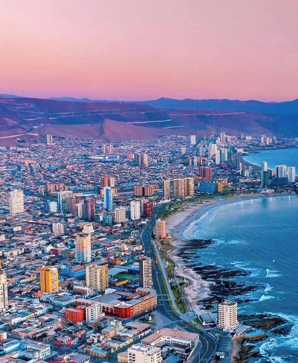 A coastal cityscape with dense urban development, a prominent road, and a beach area.