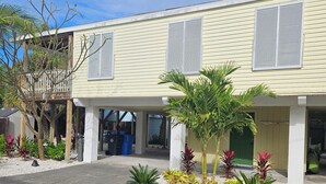 A two-story building with a covered entrance and a small garden area with various plants. - Beautiful house on Sunset Beach in Treasure Island with outdoor balcony. (Treasure Island)