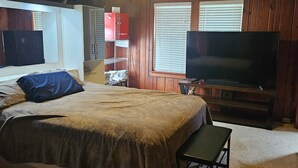 A bedroom with a bed, a TV, a ceiling fan, and wooden walls. - Beautiful house on Sunset Beach in Treasure Island with outdoor balcony. (Treasure Island)