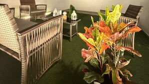 An outdoor seating area with wicker furniture, a potted plant, and a small table with decorative items. - Alma Nomada Luxury Villa & Private Pool & BBQ & Solarium (Corralejo)