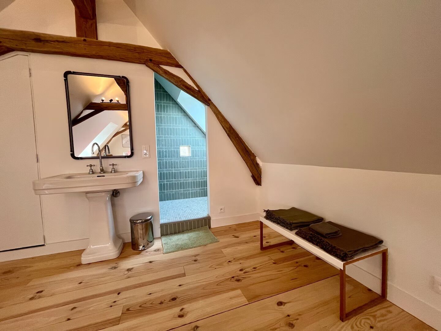 A bathroom with a white sink, mirror, and wooden beams.