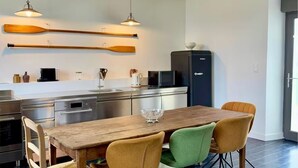 Et moderne køkken med træskabe, et spisebord med stole og hængende lamper.