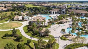 Ein Wohngebiet mit einem zentralen Schwimmbad, mehreren Sitzbereichen und einem Golfplatz im Hintergrund.