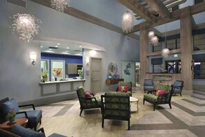 A lobby with a reception desk, seating area with chairs, and hanging lights. - 6-Bedroom Single House in Champions Gate (Four Corners)
