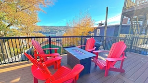 A deck with red Adirondack chairs, a glass-top table, and a view of a cityscape. - Beautifully restored 4-bdr w/ 4 ensuites. G&J on Queen's located downtown! (St. John's)