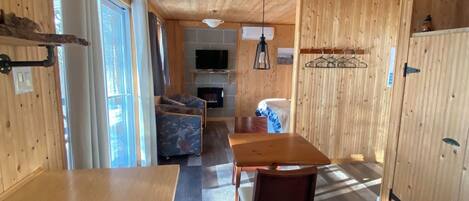Un interior de madera con una mesa de comedor, sillas, un sofá y un televisor.