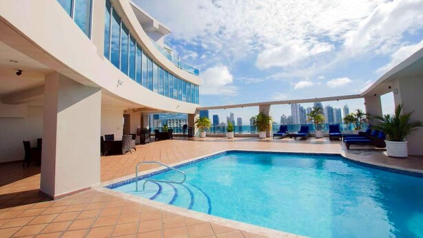 A rooftop pool area with a city view, lounge chairs, and a modern architectural design. - YC 1701l Apartamento 2 BDR Av Balboa (Panama City)