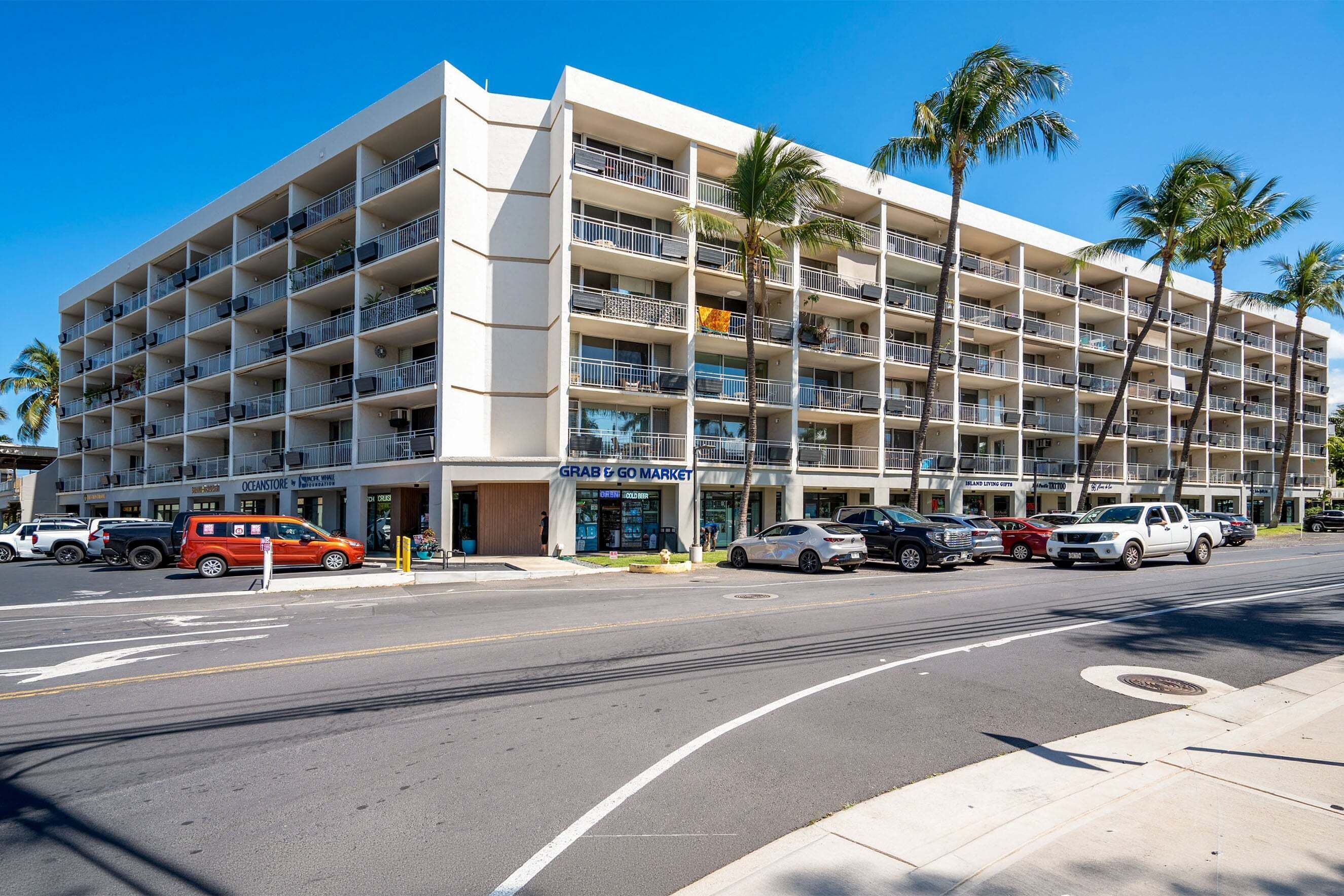 A multi-story hotel with balconies, a 'Grab & Go Market' sign, and parked cars along the street.