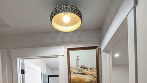 Un pasillo con piso estampado, un cuadro de un faro y una lámpara en el techo.