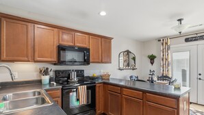 Una cocina con armarios de madera, un microondas negro, una estufa y un lavabo.