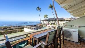 A balcony with a view of the ocean, a pool, and palm trees. - Shores of Maui 215 - Dramatic Ocean Views, Steps to the Beach, Renovated, AC! (Kihei)