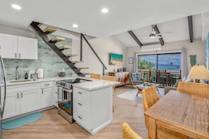 A modern kitchen with white cabinets, a built-in oven, and a staircase with wooden steps. - Shores of Maui 215 - Dramatic Ocean Views, Steps to the Beach, Renovated, AC! (Kihei)