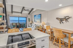 Une cuisine moderne avec vue sur l’océan, des meubles en osier et un coin repas.