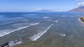 A coastal view with waves, beach, and distant mountains. - Shores of Maui 215 - Dramatic Ocean Views, Steps to the Beach, Renovated, AC! (Kihei)