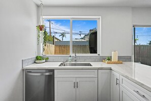 Eine moderne Küche mit großem Fenster, Edelstahlgeräten und einem Holzzaun im Freien.