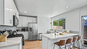 A modern kitchen with white cabinets, stainless steel appliances, and a large island with bar stools. - Hot Tub - Firepit - Prime Location - Belmont Shore Retreat - FIFA 2026 (Long Beach)