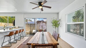 A modern kitchen with a dining area, a ceiling fan, and a view of the backyard. - Hot Tub - Firepit - Prime Location - Belmont Shore Retreat - FIFA 2026 (Long Beach)