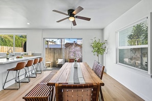 Une cuisine moderne avec un coin repas, un ventilateur de plafond et une vue sur le jardin arrière.
