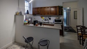 Et moderne køkken med træskabe, en central ø, barstole og et spiseområde med et bord og stole.