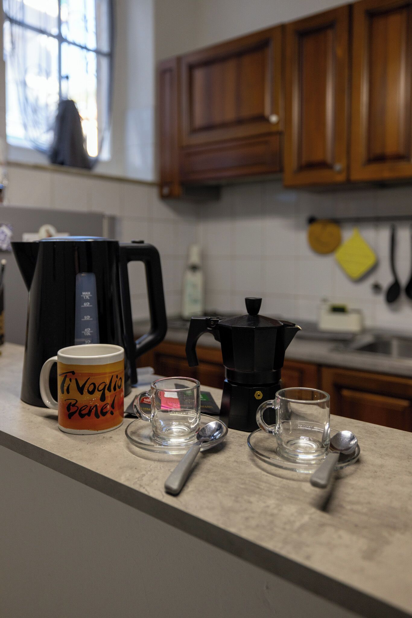 A kitchen counter with a coffee maker, a mug, and two glasses.