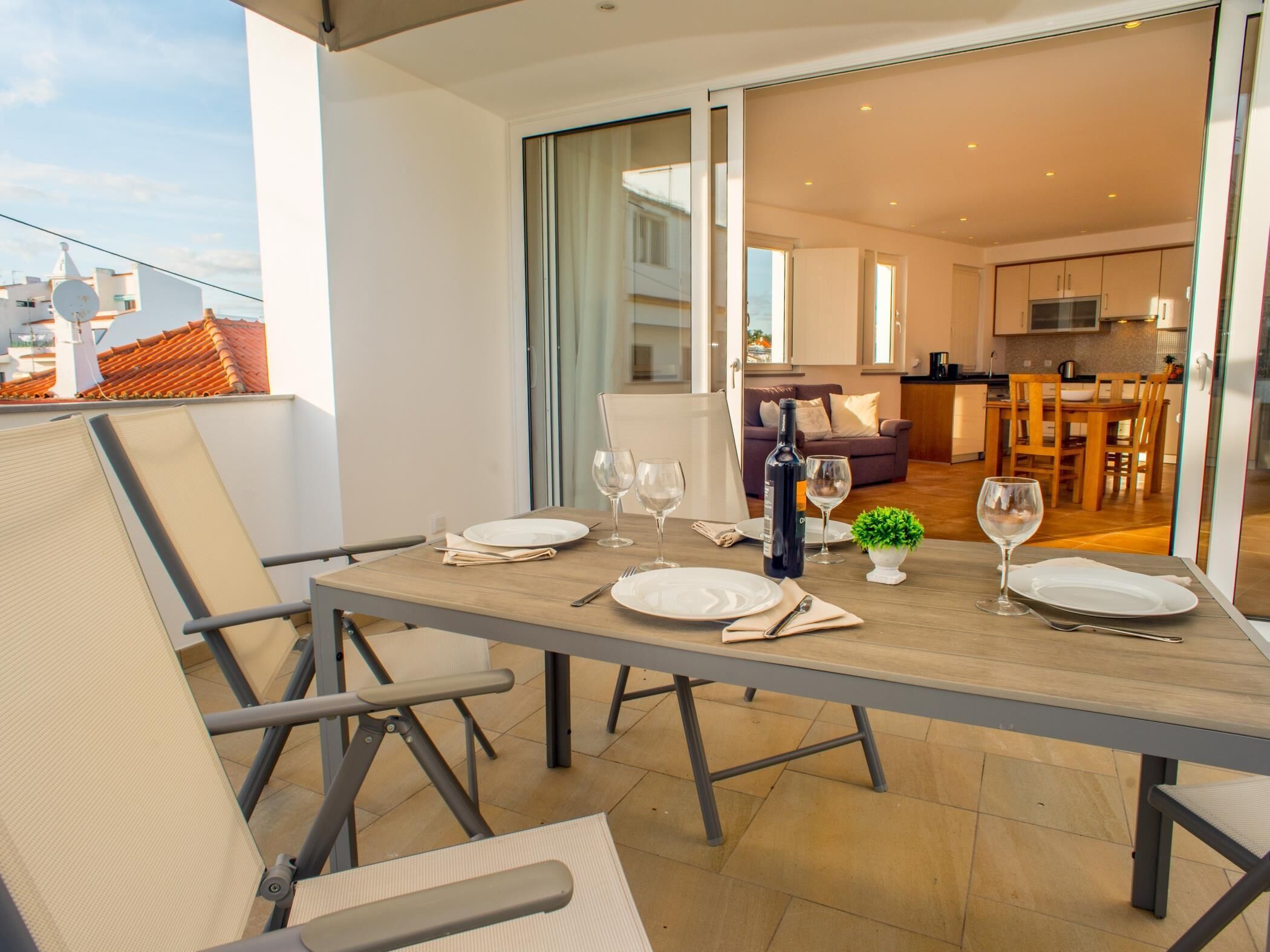A dining area with a table set for four, a sofa, and a kitchen in the background.