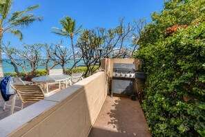 An outdoor patio with a grill, seating area, and a view of the ocean. - Punahoa Beach 201 - Direct Ocean Front, Beautiful Renovation, Split AC, Wi-fi (Kihei)