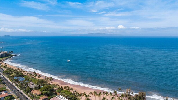A coastal view with a beach, ocean, and a road leading to a residential area. - Punahoa Beach 201 - Direct Ocean Front, Beautiful Renovation, Split AC, Wi-fi (Kihei)