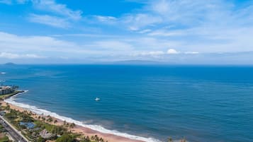 Vista costera con playa, océano y una carretera que lleva a una zona residencial.