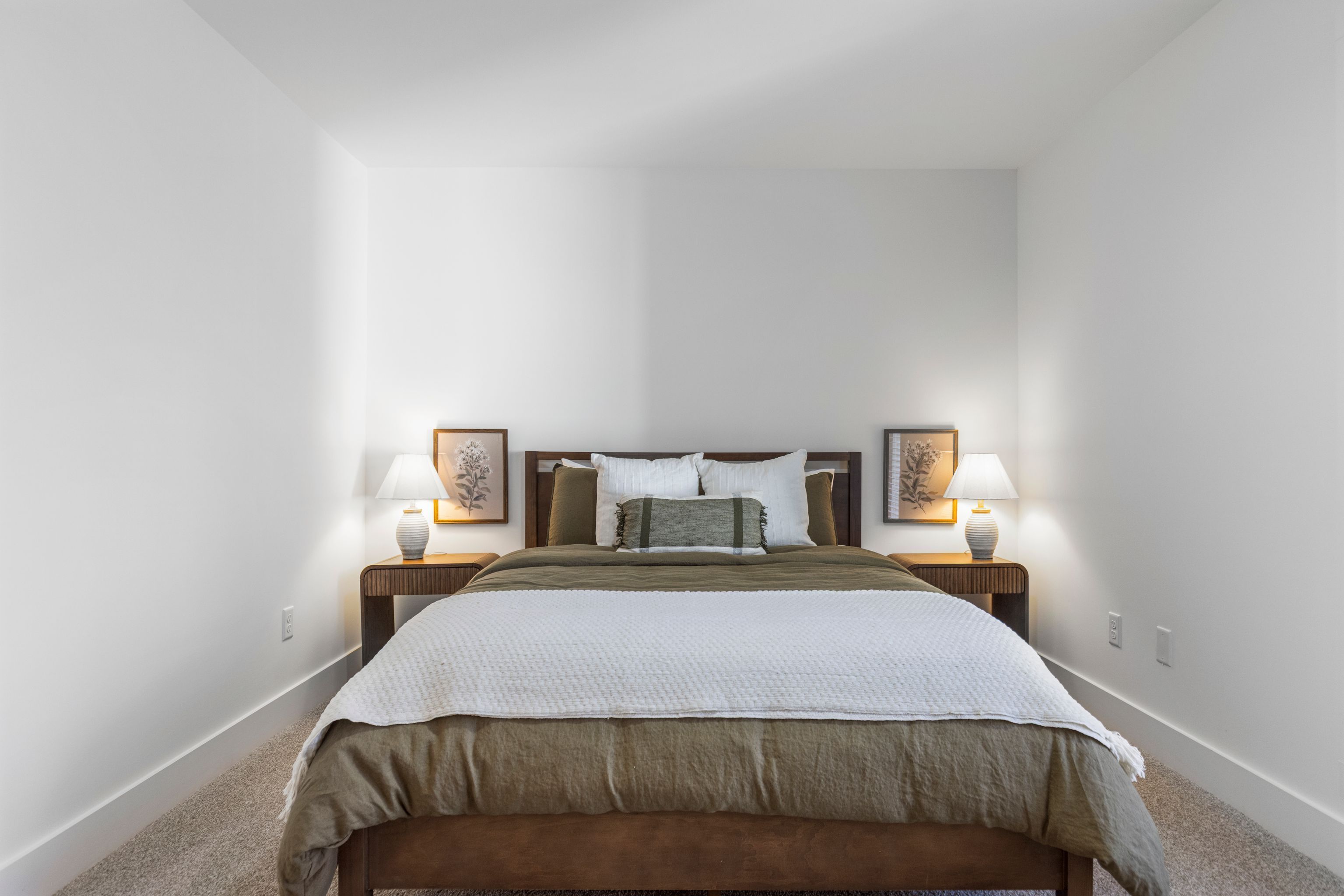 Une chambre à coucher avec un lit, deux tables de chevet et deux lampes.