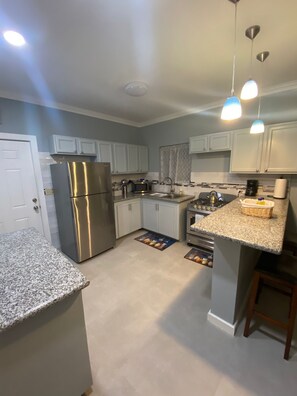 A modern kitchen with white cabinets, stainless steel appliances, granite countertops, and pendant lighting. - 2-bedroom townhome in delightful Nassau with AC comfort (Nassau)