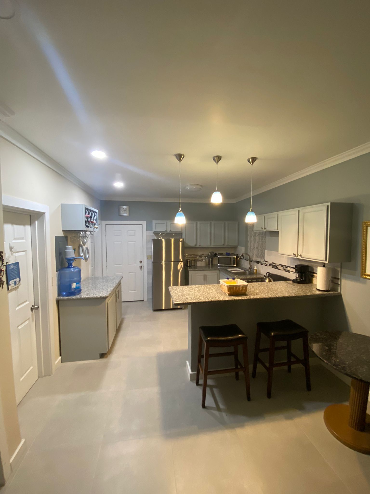 A modern kitchen with a central island, pendant lighting, and a water dispenser.