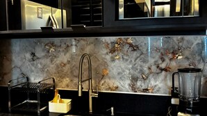 Een moderne keuken met een marmeren achterwand, roestvrijstalen apparatuur en een zwart aanrecht.