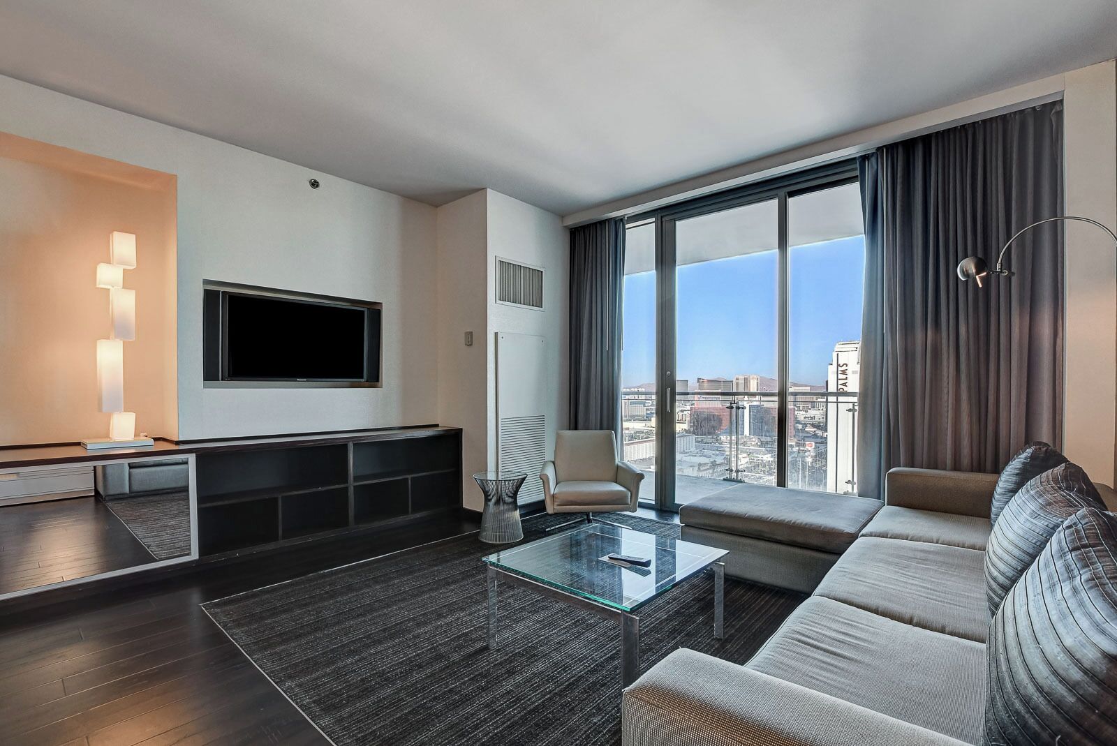 A modern living room with a large window, a flat-screen TV, a sofa, and a coffee table.