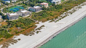 An aerial view of a coastal area with a beach, buildings, and a tennis court. - Sanddollar B302: New Top-Floor 3BR Luxury Beachfront Condo on Sanibel (Sanibel)