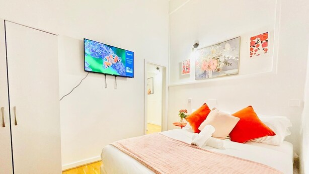 Une chambre d’hôtel avec un lit, un téléviseur fixé au mur et une armoire.