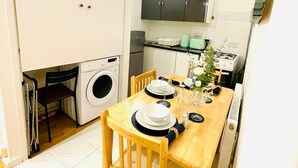 Une cuisine compacte avec un coin repas, un lave-linge et une petite table mise pour deux personnes.