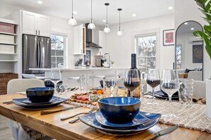 Una cocina moderna con armarios blancos, un refrigerador de acero inoxidable e iluminación colgante.
