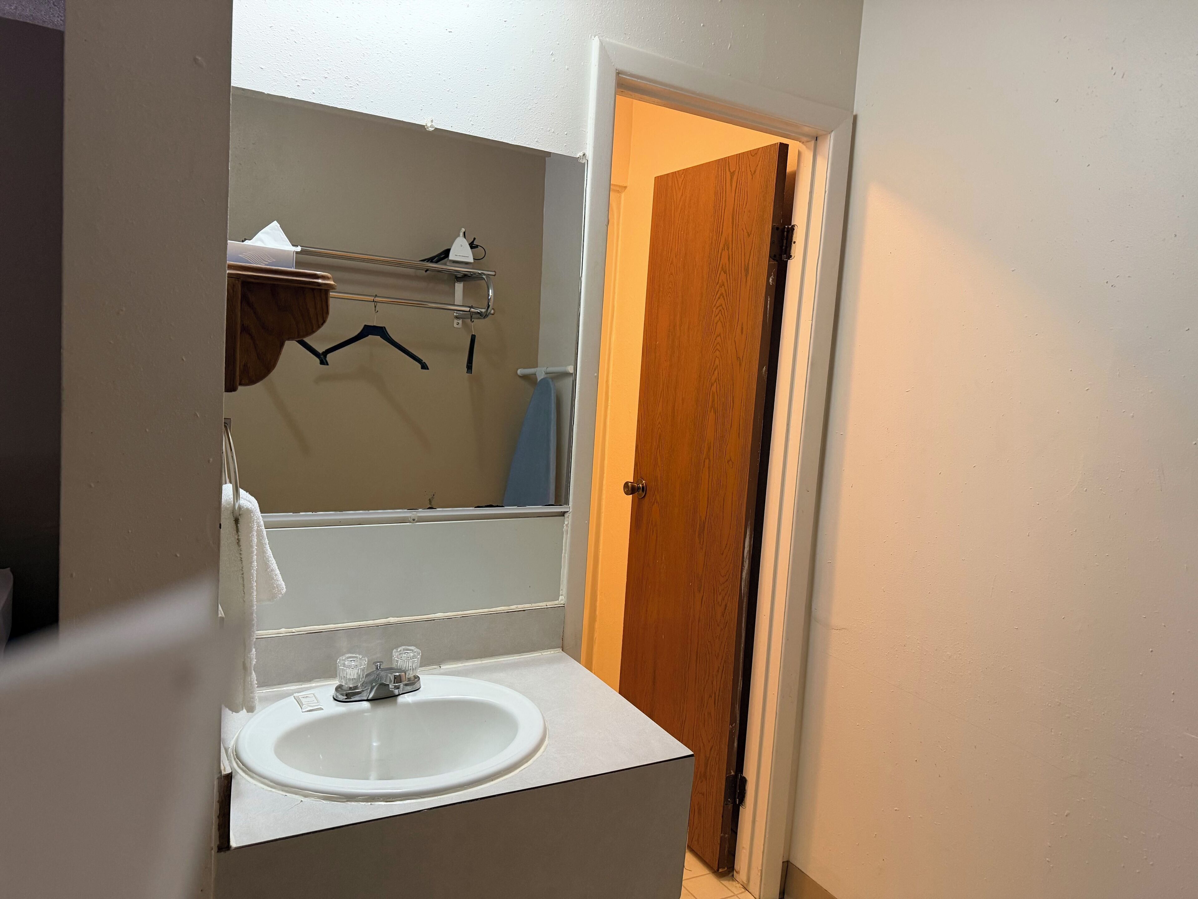 A bathroom with a white sink, a mirror, and a wooden door.