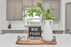 A kitchen with a white countertop, a wooden tray, a white pitcher, a small sign, and a potted plant. - Eado Bon Temps Serene 4-bedroom house with private rooftop Hot Tub - Minutes ... (Houston)