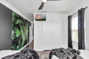 A bedroom with a bed, a ceiling fan, a TV, and a door. - Fall Discounts -Private Rooftop Hot Tub - Minutes to Downtown- Skyline Views (Houston)