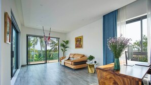 Un vaste espace de vie comprenant un canapé, une table basse et une table d’appoint en bois.