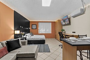A compact hotel room with a bed, sofa, desk, and TV. - Centro Histórico | Cochera | Mini split | Wifi (Durango)