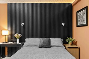 A modern bedroom with a bed, bedside tables, a desk, and a wall-mounted light fixture. - Centro Histórico | Cochera | Mini split | Wifi (Durango)